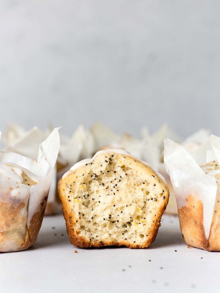 Lemon Poppy Muffins sliced in half with lots of other muffins in paper wrapping.
