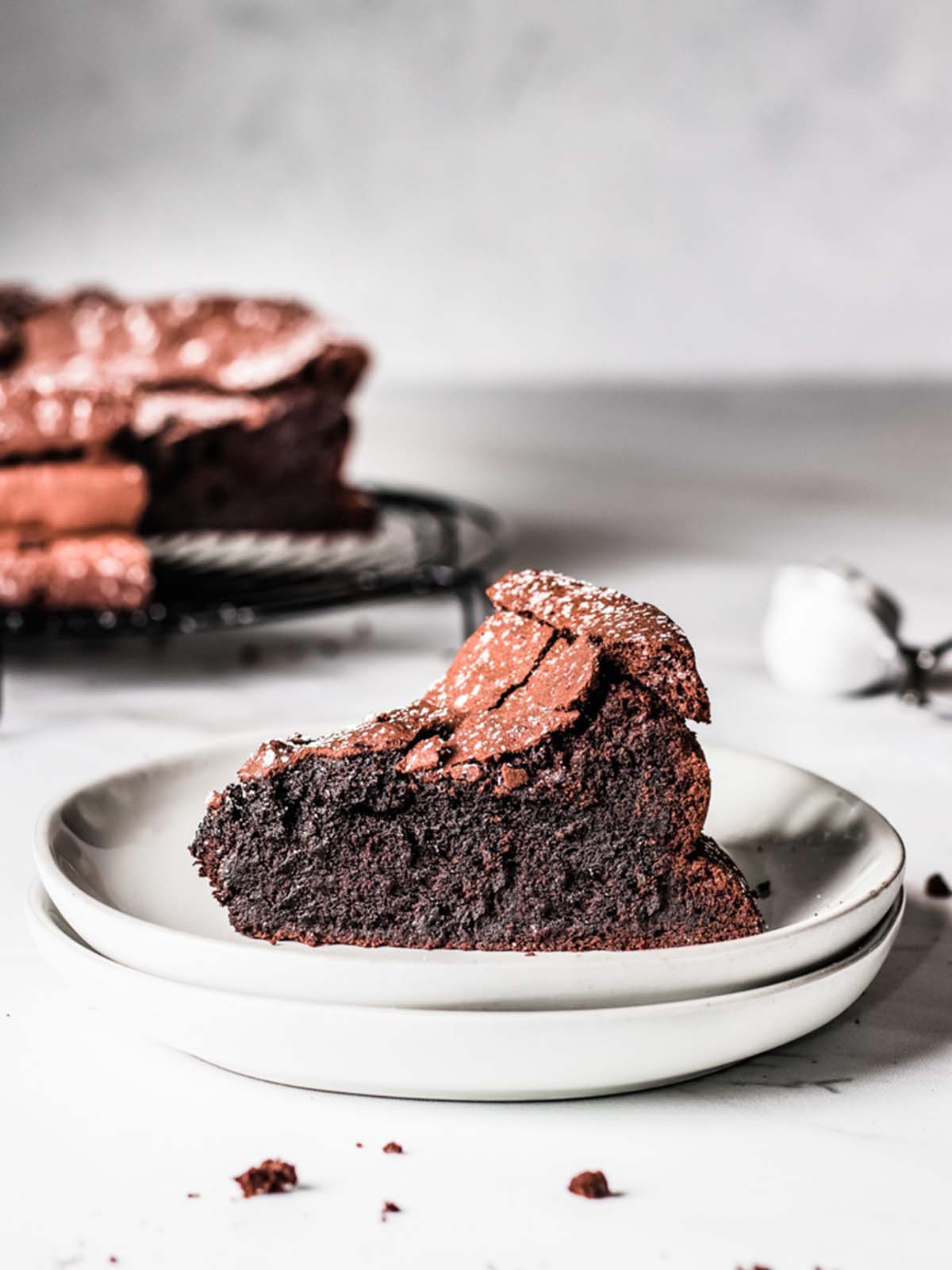 Chocolate Cake slice on stack of plates with remaining cake in back.