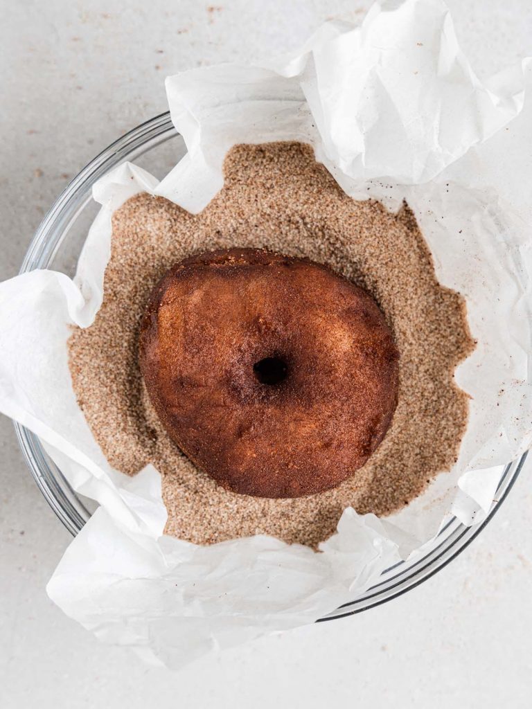 Donut in bowl of cinnamon sugar.