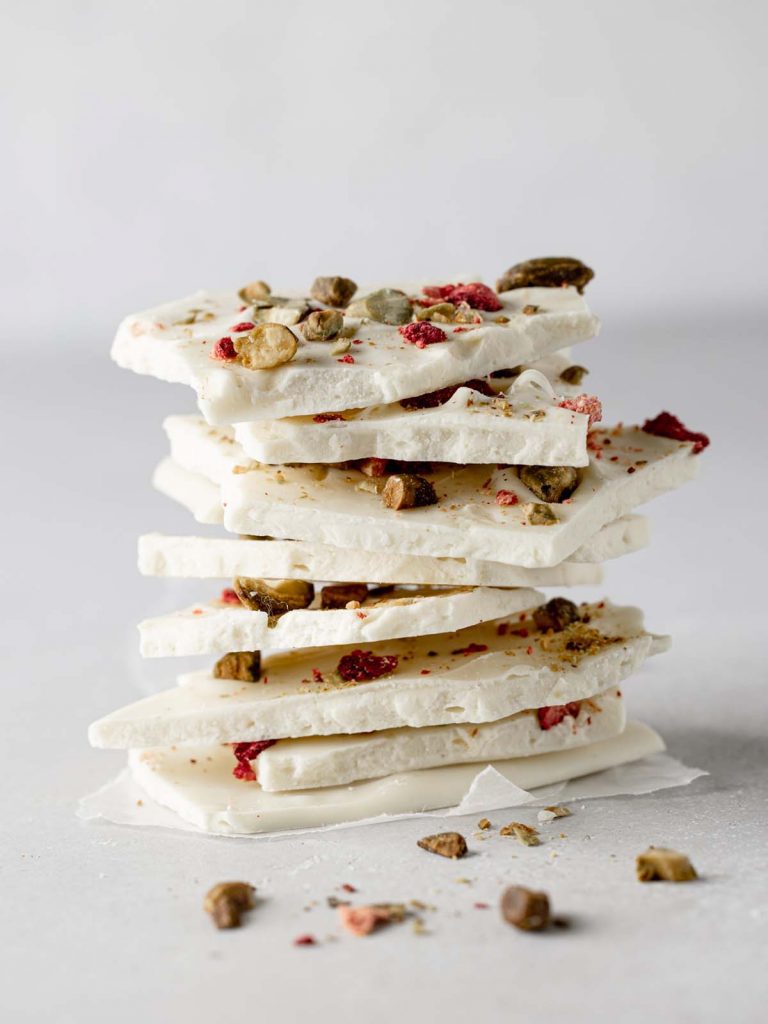 Stack of white chocolate bark pieces with chopped pistachios and strawberries.