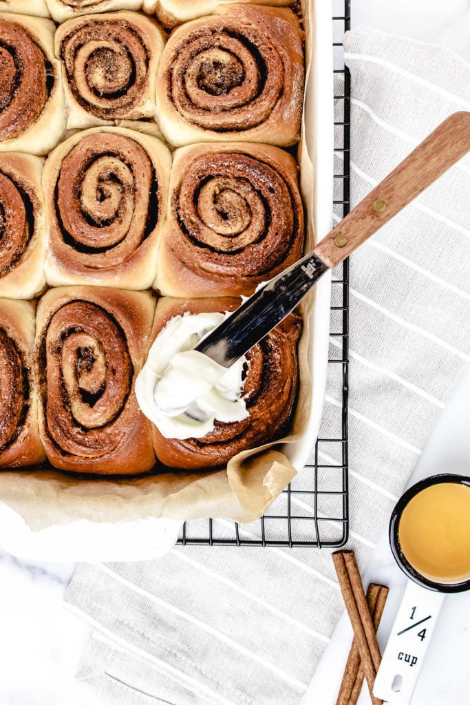 Placing icing on cinnamon rolls