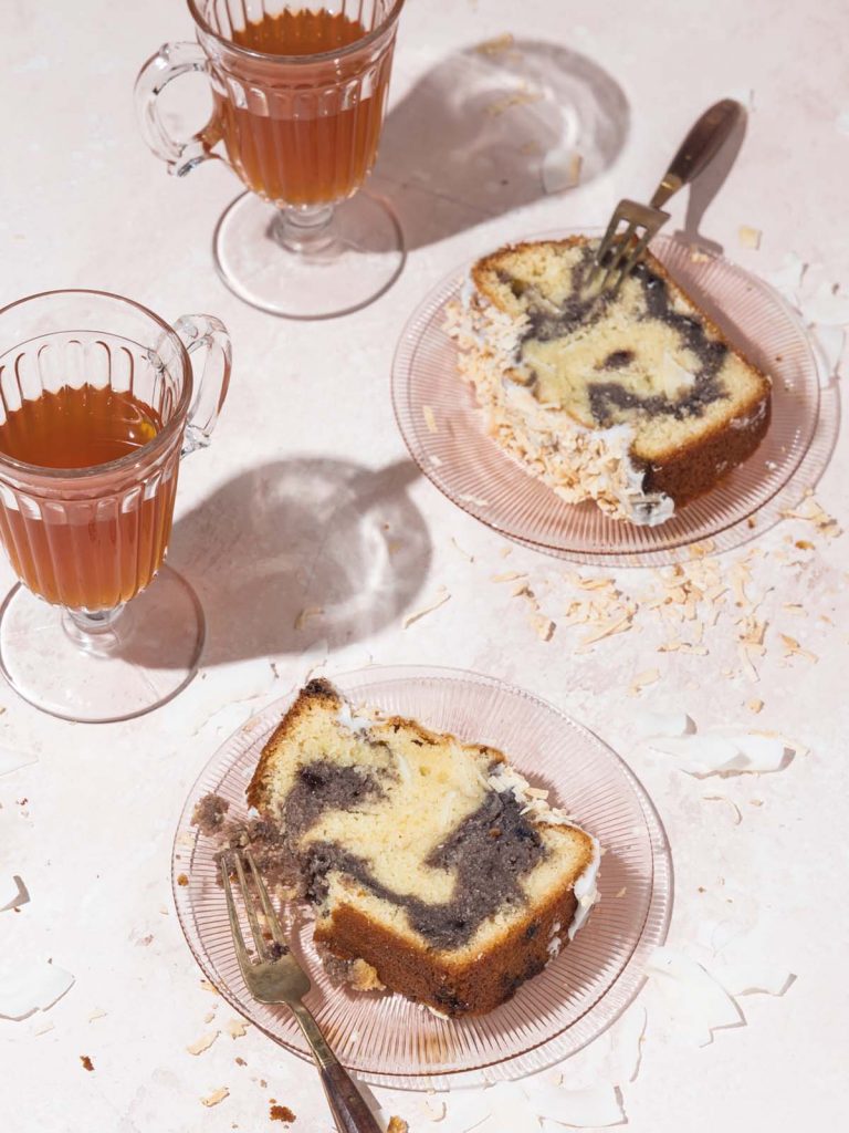 Coconut Pound Cake Sliced on two plates with glass mugs filled with tea.