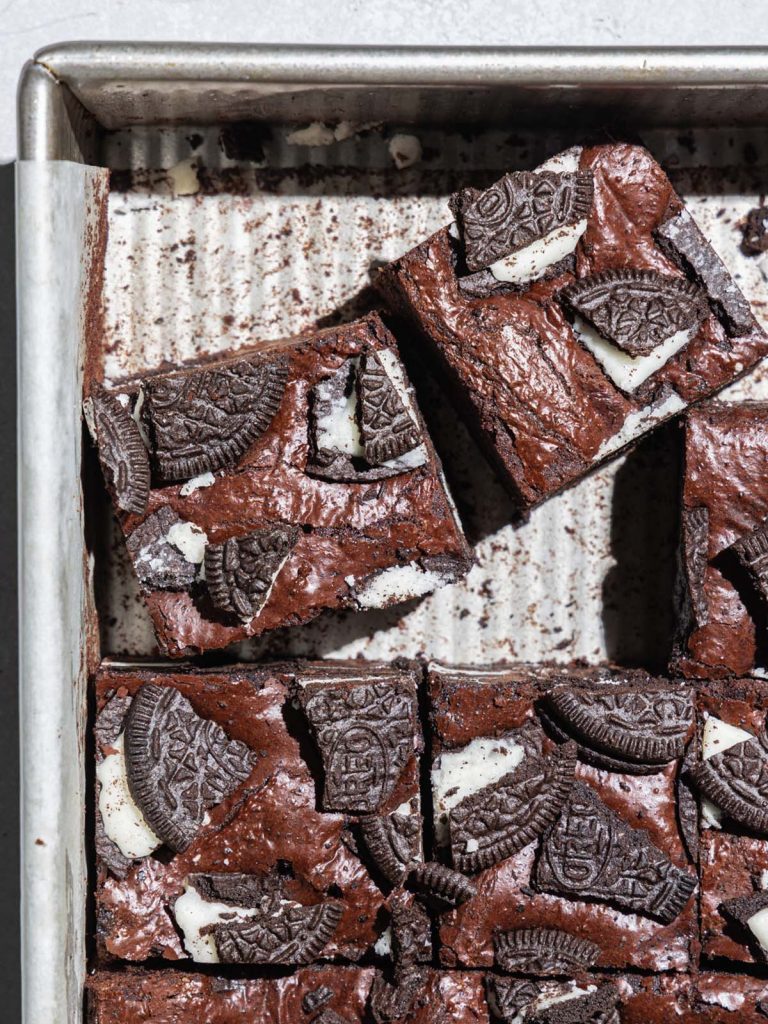 Brownies sliced in baking tray with Oreos on top.