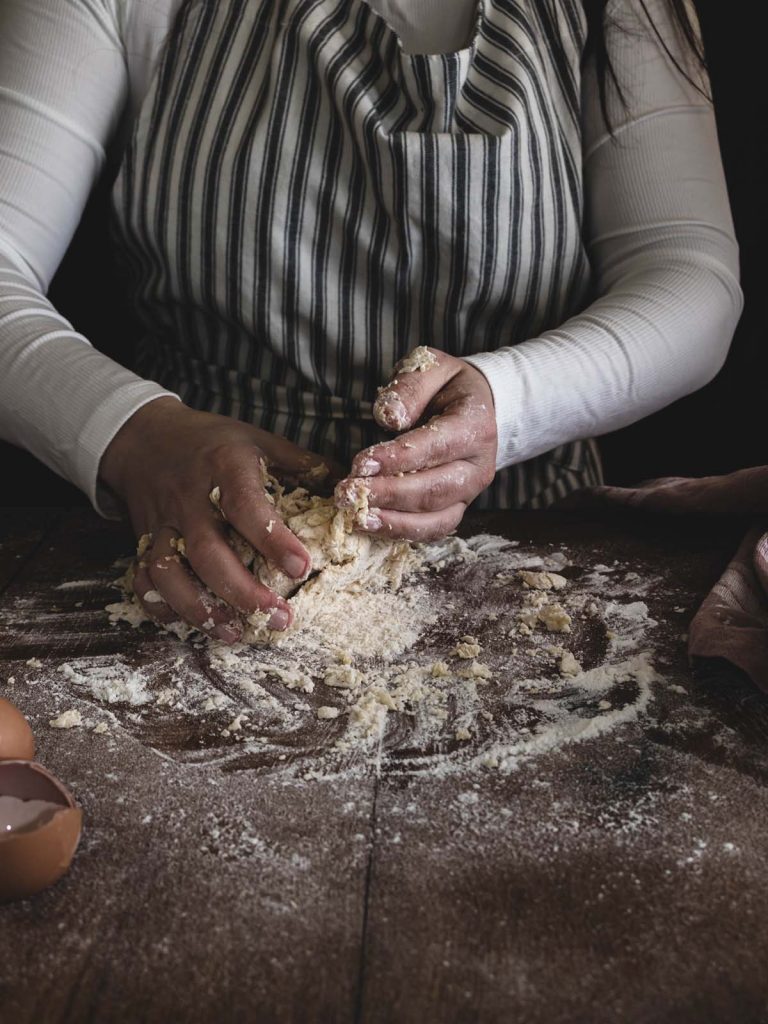 Chef incorporating flour into pasta dough.