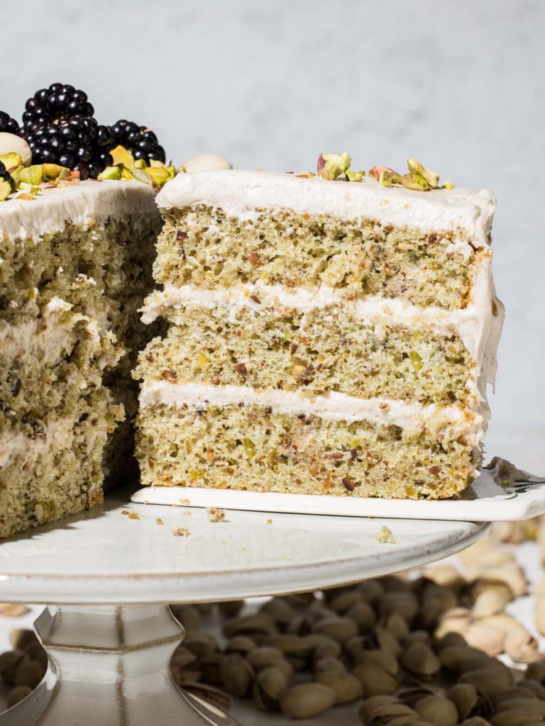 Pistachio Cake slice being removed on cake stand.