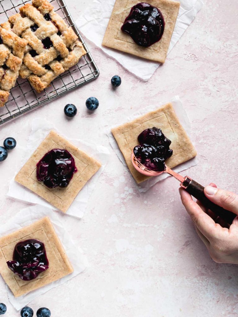 Placing filling on hand pies with measuring spoon.