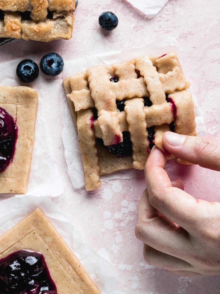 Making lattice topping of hand pies with uncovered pies at the side.