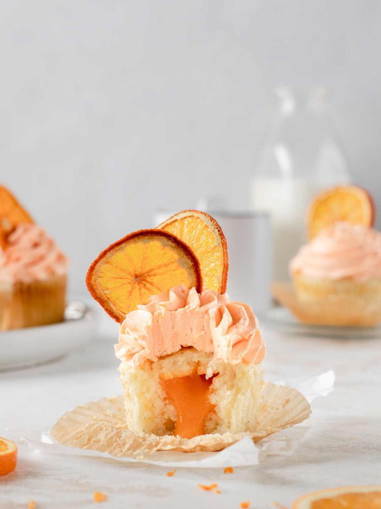 Orange Cupcake on cupcake liner with bite removed and dried orange slice decoration