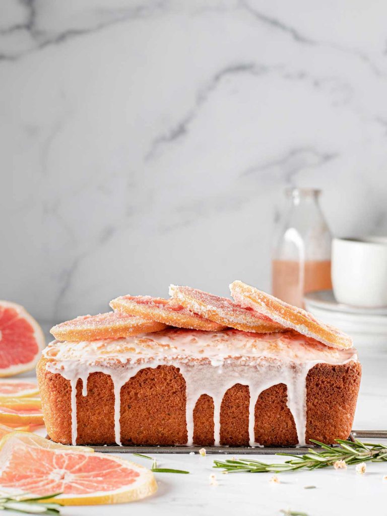 Olive oil loaf cake from the side with drizzle and candied grapefruit slices on top.