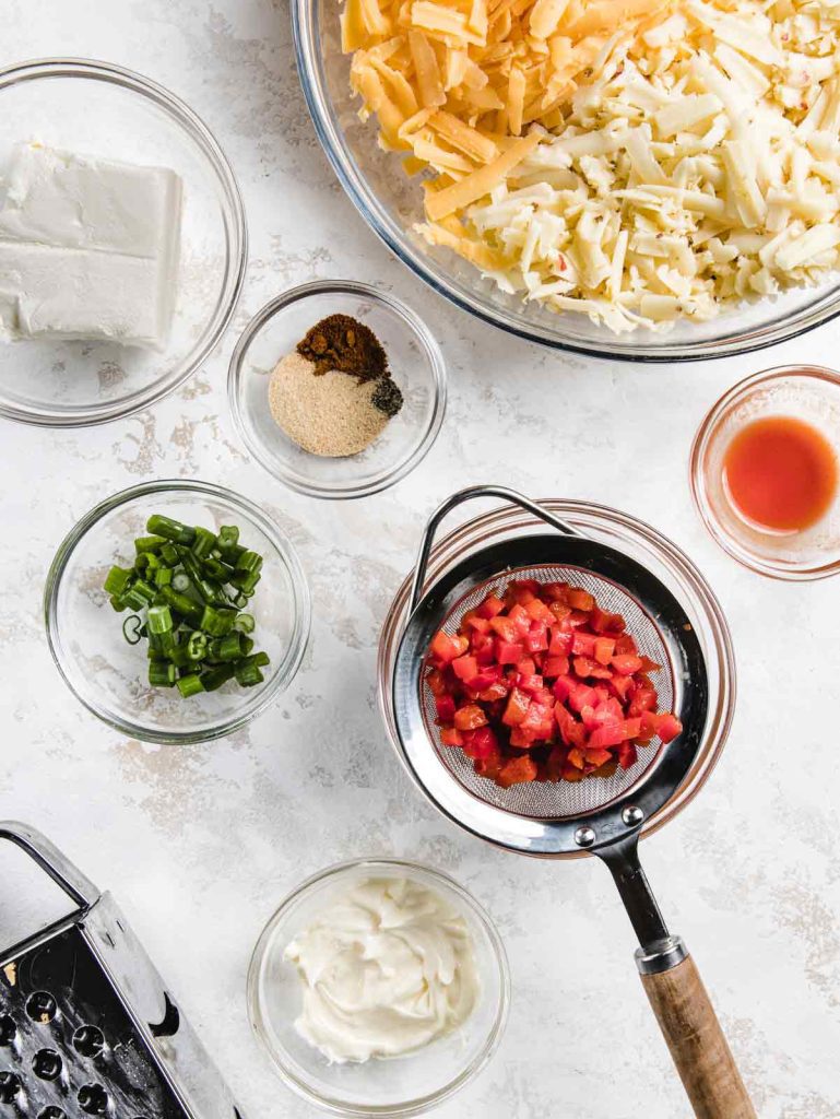 Pimento cheese ingredients in small glass bowls.