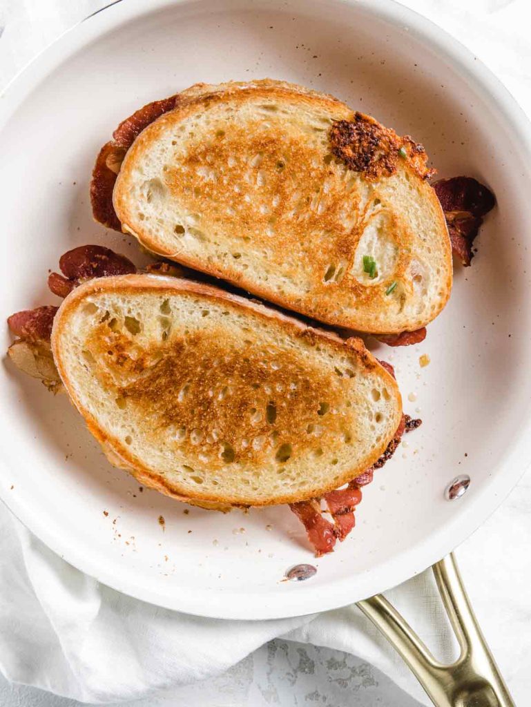 Two grilled cheese sandwiches in white skillet.