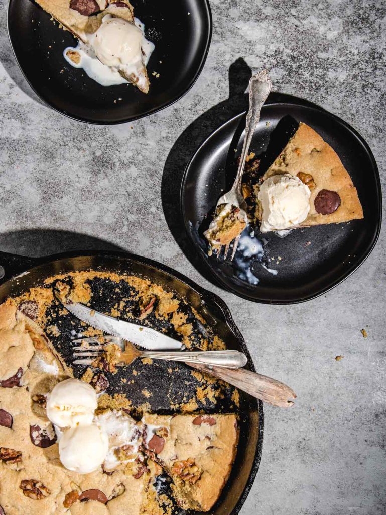 2 slices of cookies and pan with used fork and knife with scoops of ice cream.