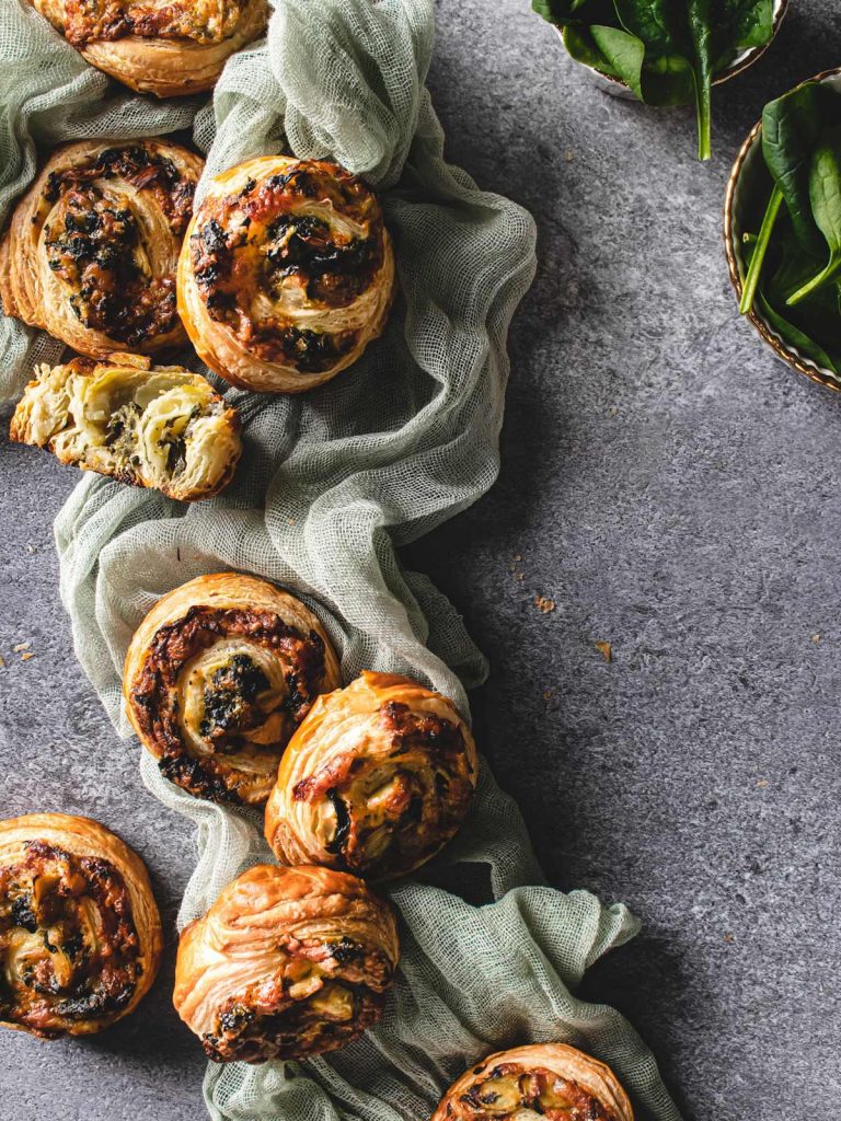 Swirled Puffs sitting on green cloth with fresh spinach on the side