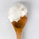 A wooden spoon with scoop of buttercream.