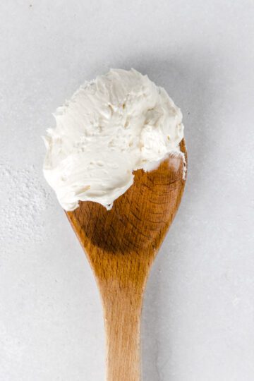 A wooden spoon with scoop of buttercream.