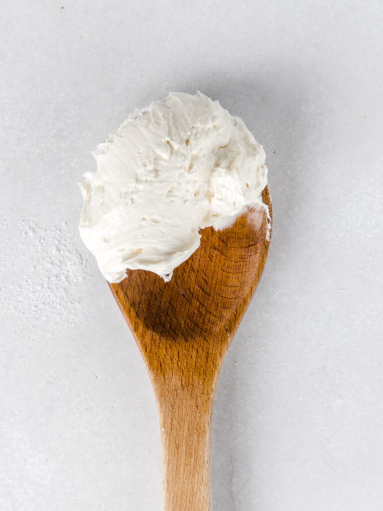 Scoop on buttercream on a wooden spoon.