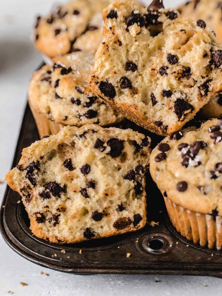 Side view of cut open muffins in tin with chocolate chips.