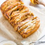 Bread on marble with drizzle on top with orange in the background.