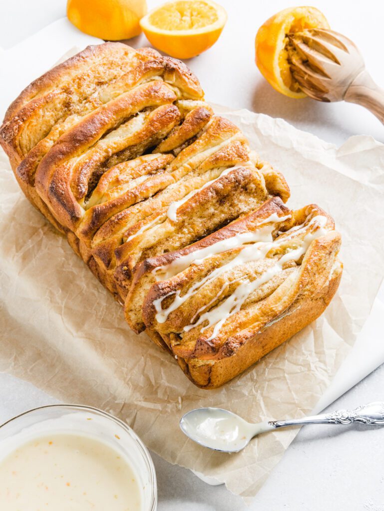 Bread on marble with drizzle on top with orange in the background.