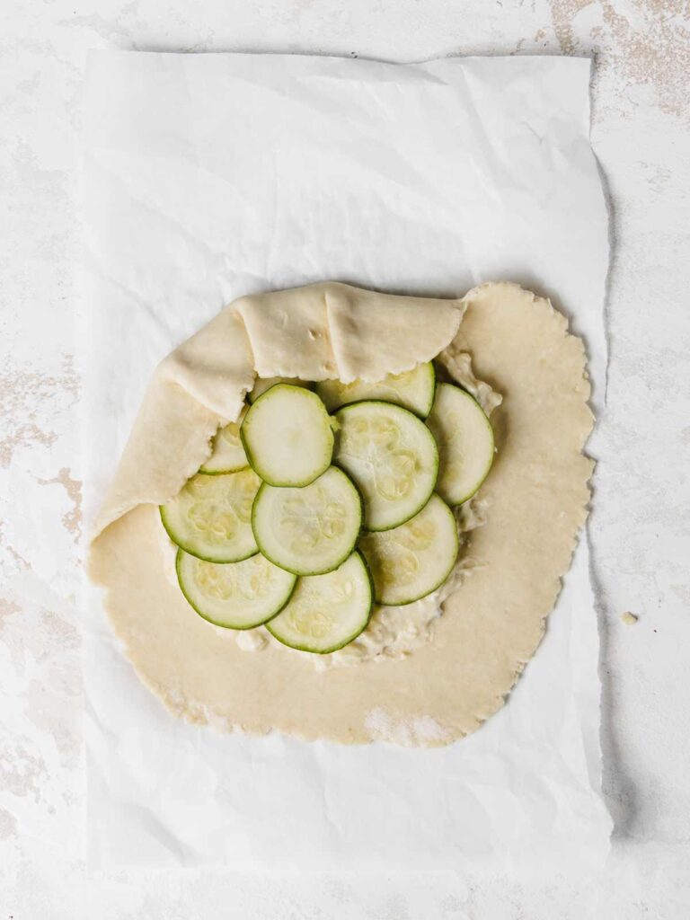 Galette with crust beginning to be folded over zucchini slices.