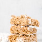 Stack of cereal treats with parchment between.