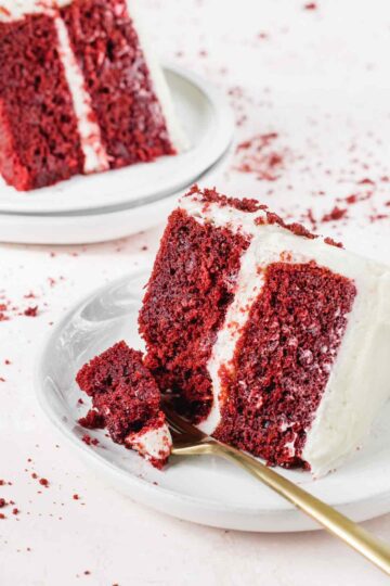Slice of red velvet cake on plates with fork.