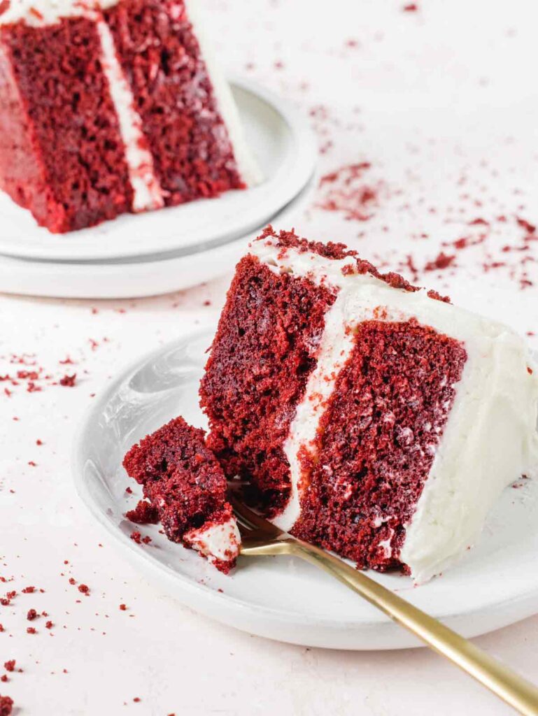 Slice of red velvet cake on plates with fork.