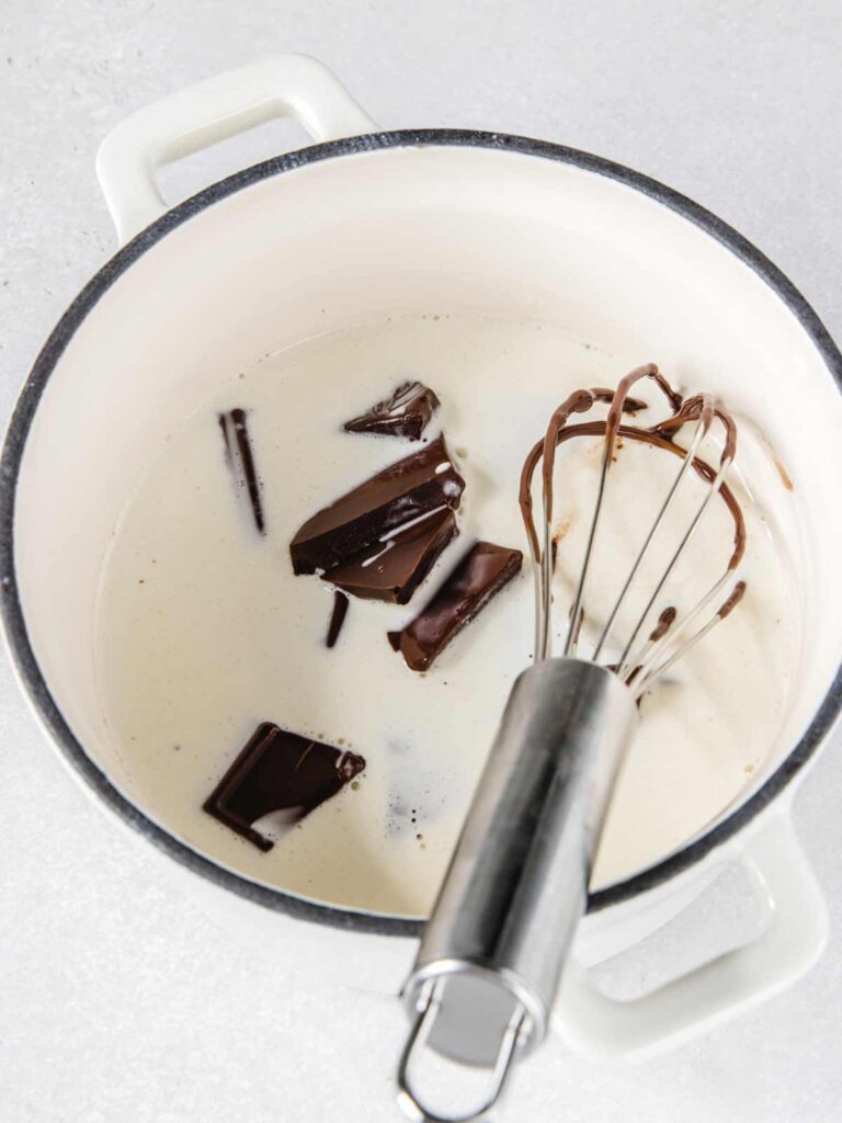 Cream and chocolate in pot with whisk.