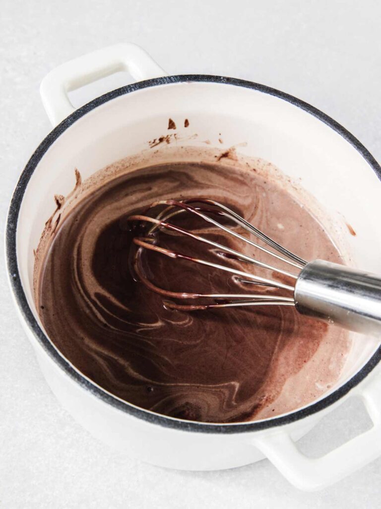 Chocolate stirred in pot with whisk.