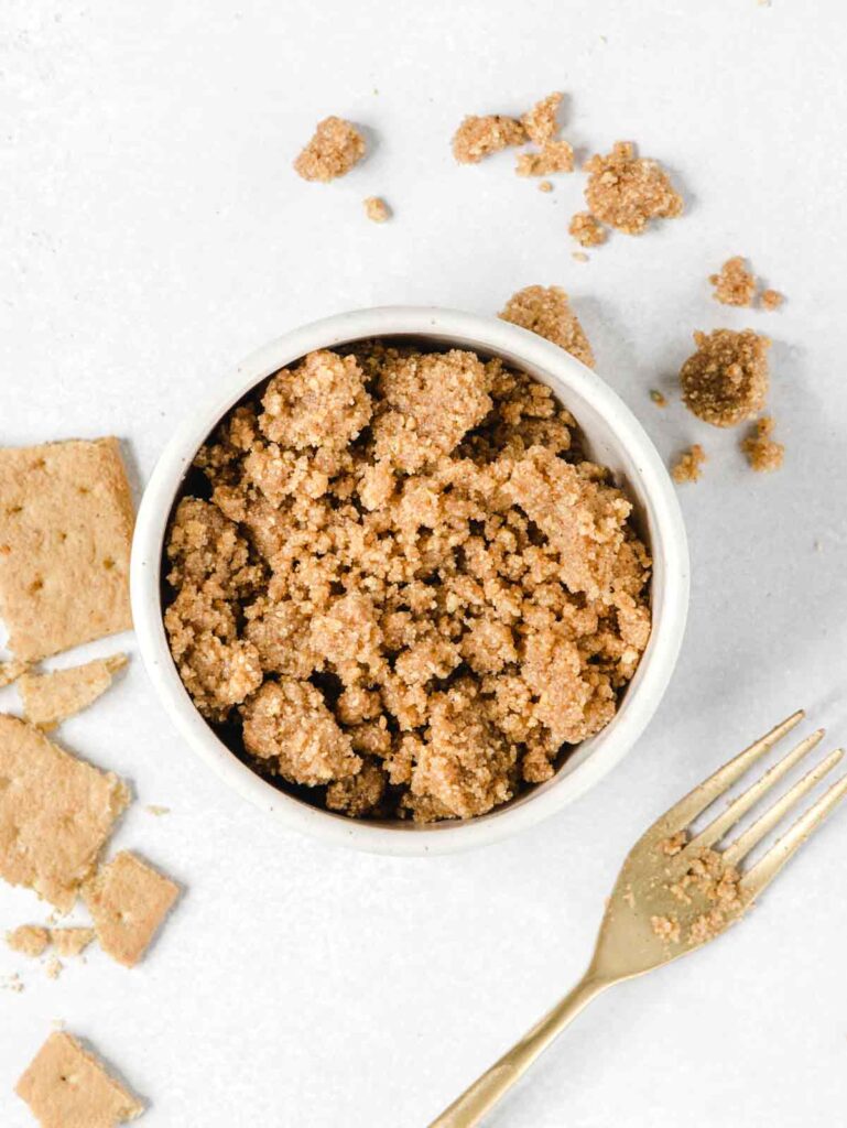 Graham cookie crumble in bowl with gold fork.