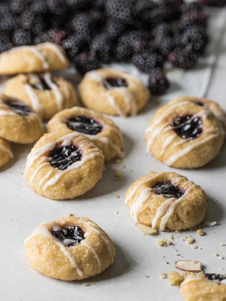 Cookies on board with blackberries in the background.