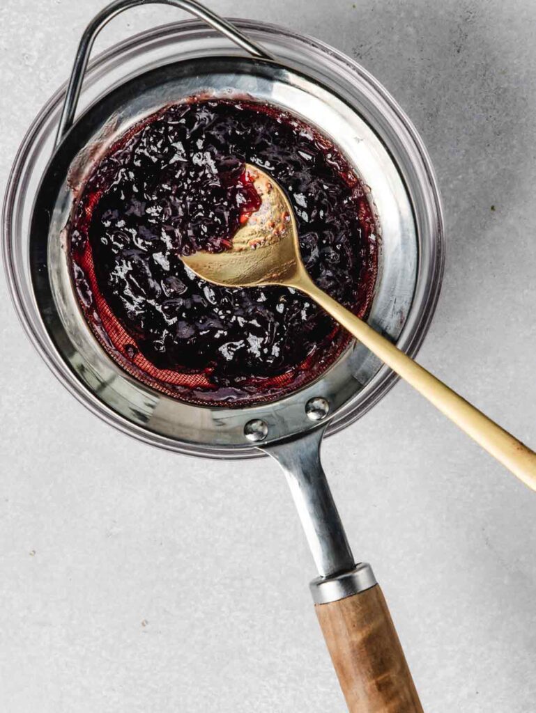 Jam in a strainer with spoon.