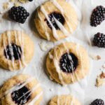 Thumbprint cookies with blackberries on parchment paper.