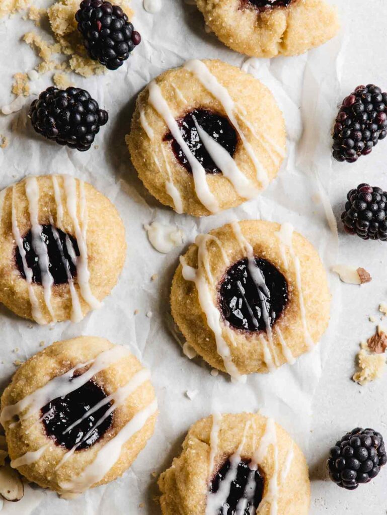 Thumbprint cookies with blackberries on parchment paper.