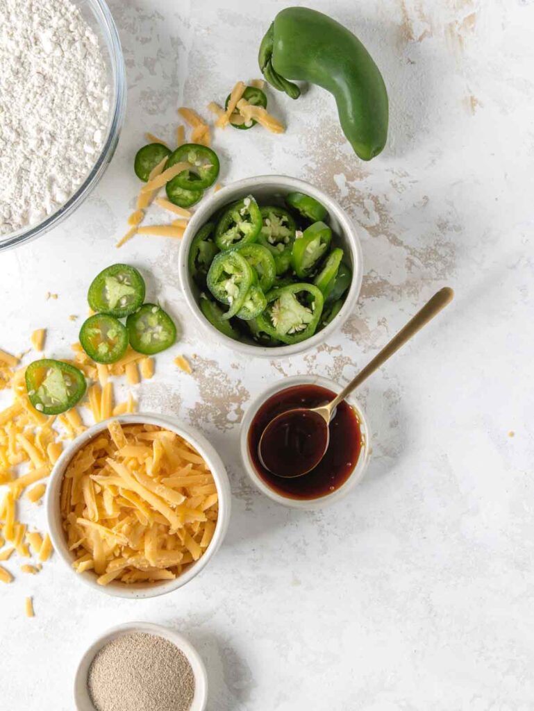 Bowls of ingredients with jalapeño slices and shredded cheddar cheese.