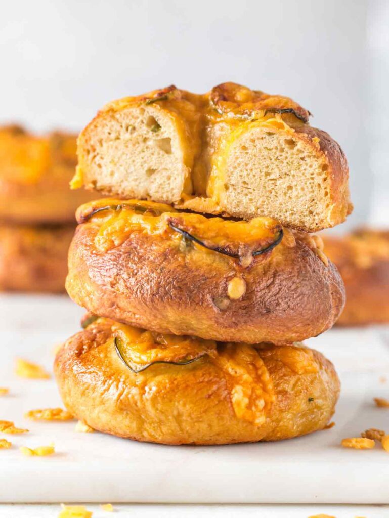 Stack of 3 bagels with top bagel sliced in half.