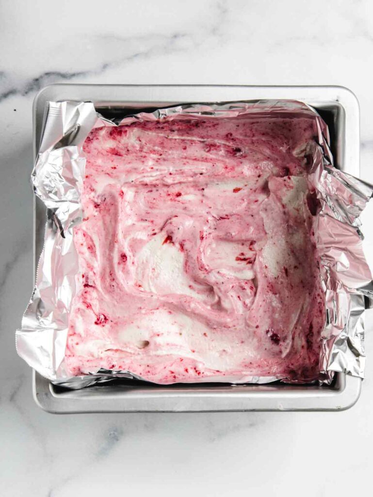 Ice cream with strawberry jam swirl in cake pan.