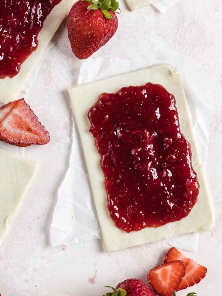 Filling squares of dough with strawberry jam.