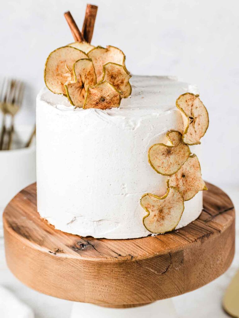 Cake on stand with dried apples and cinnamon sticks.