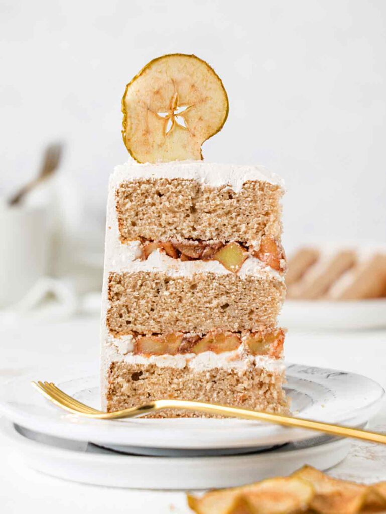 Standing slice of cake with apple compote on plate.