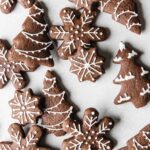 Pile of decorated gingerbread cookies on board.