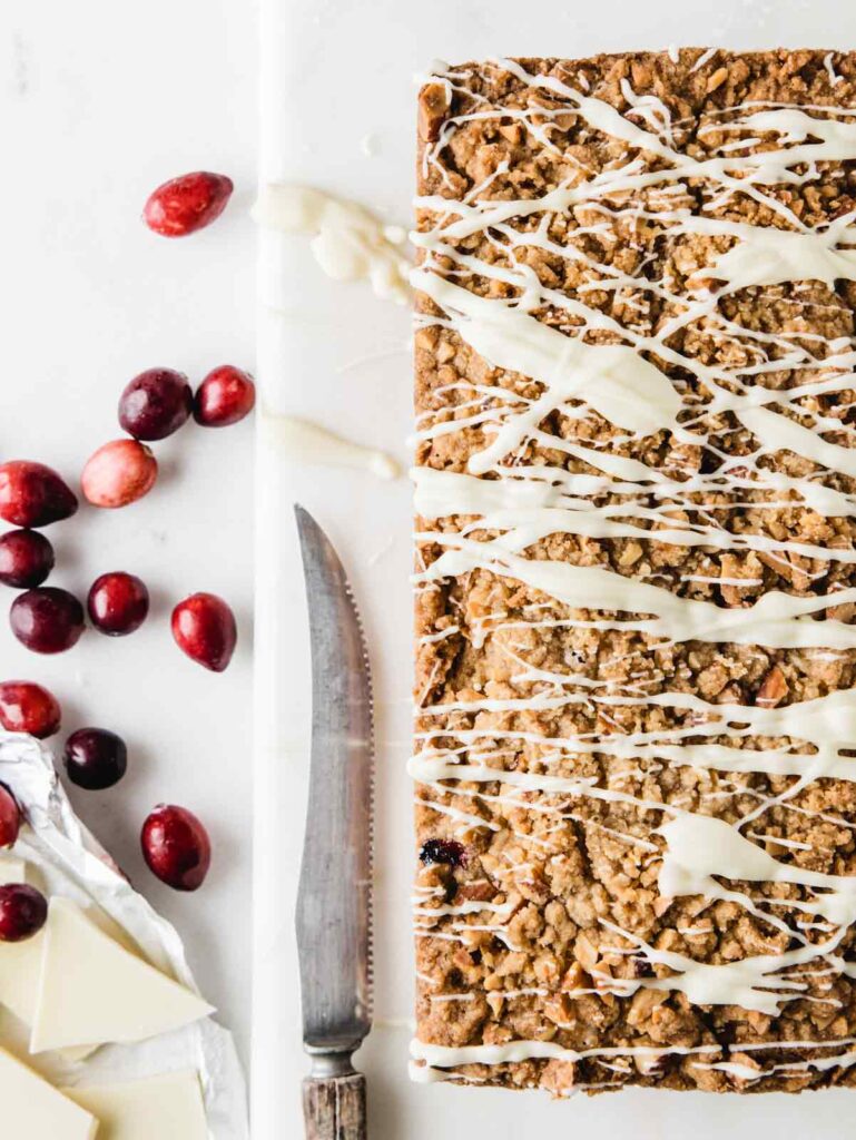 Unsliced cranberry loaf with cranberries and knife on the side.