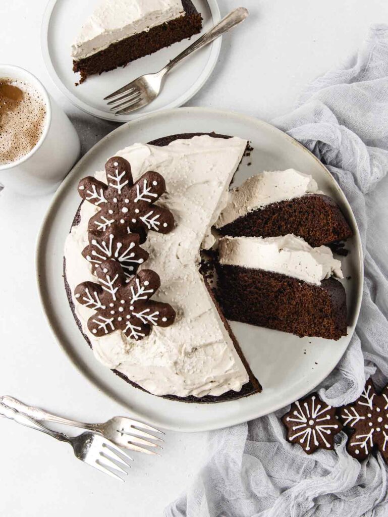 Sliced cake on plate with coffee mug and cookies on top.