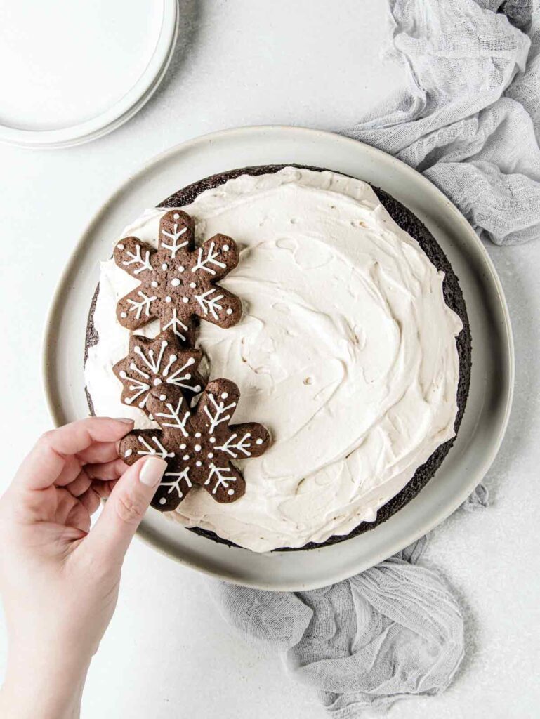 Placing cookies on top of gingerbread cake.