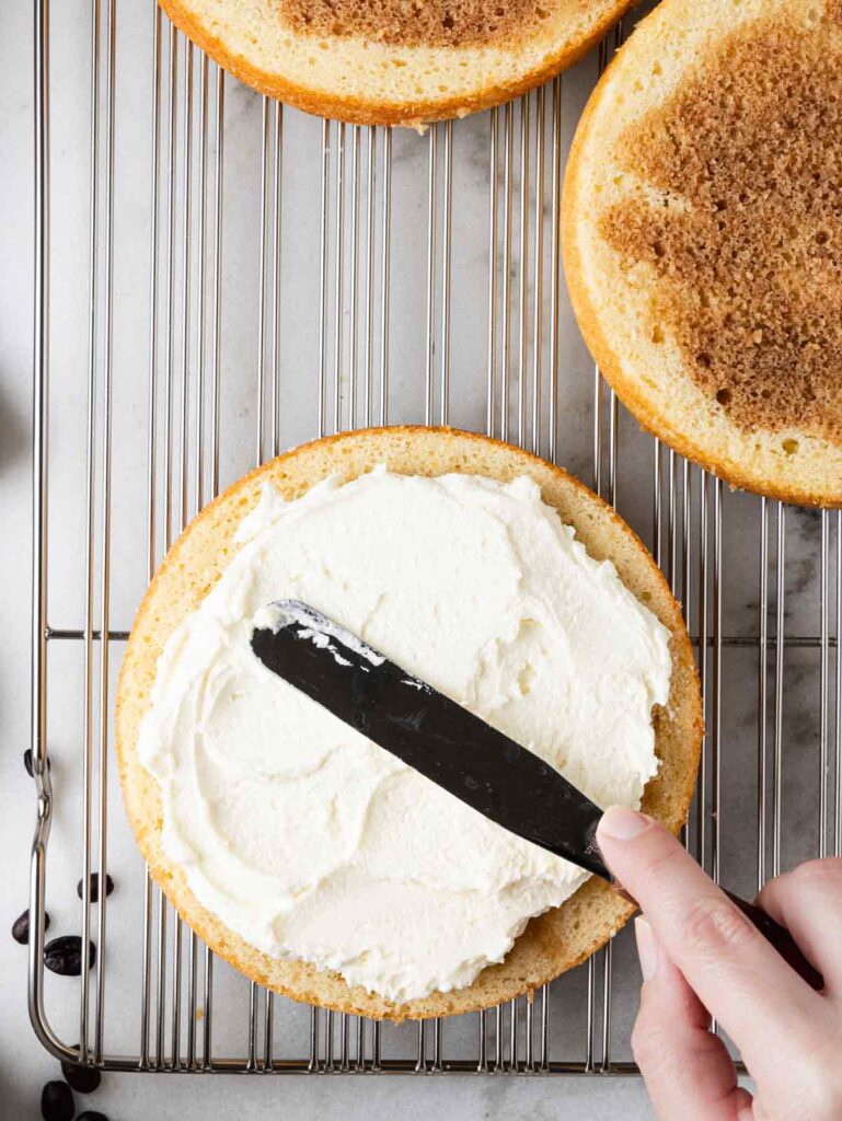 Spreading mascarpone whipped cream on cake layer.