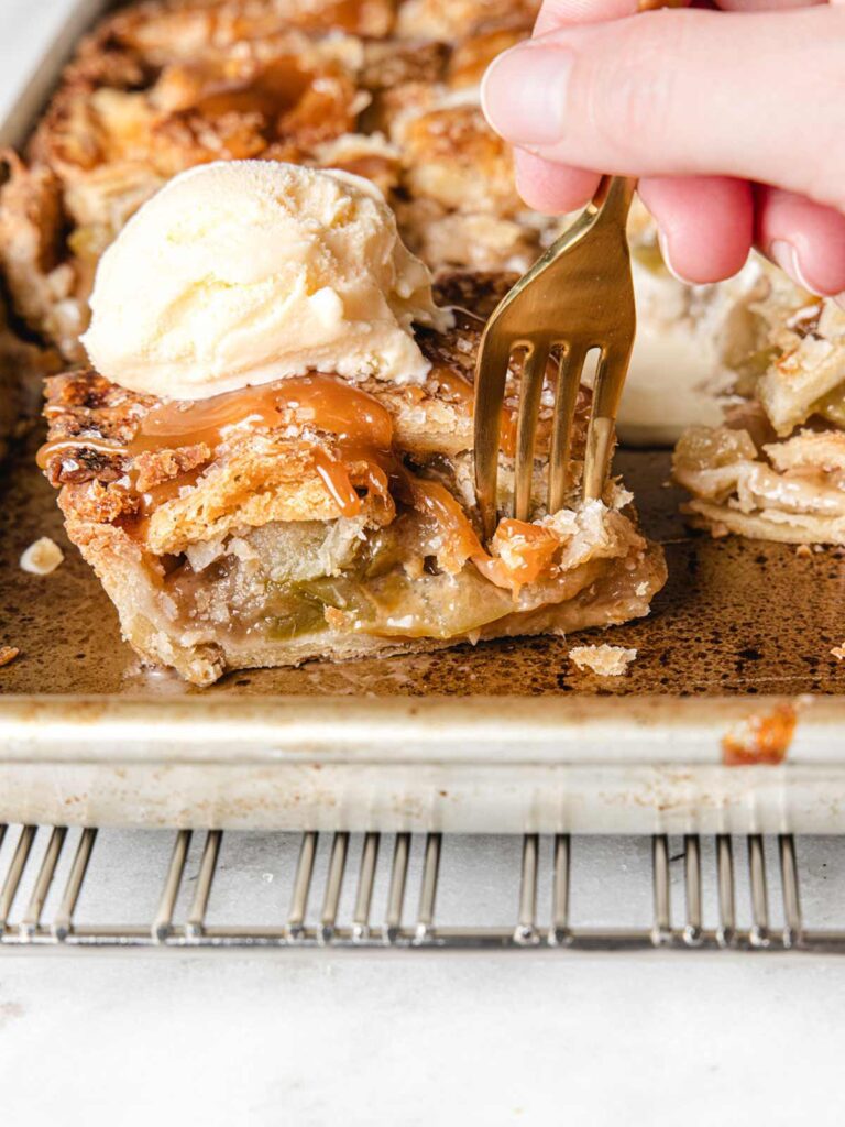 Close of up fork going through apple pie with ice cream.