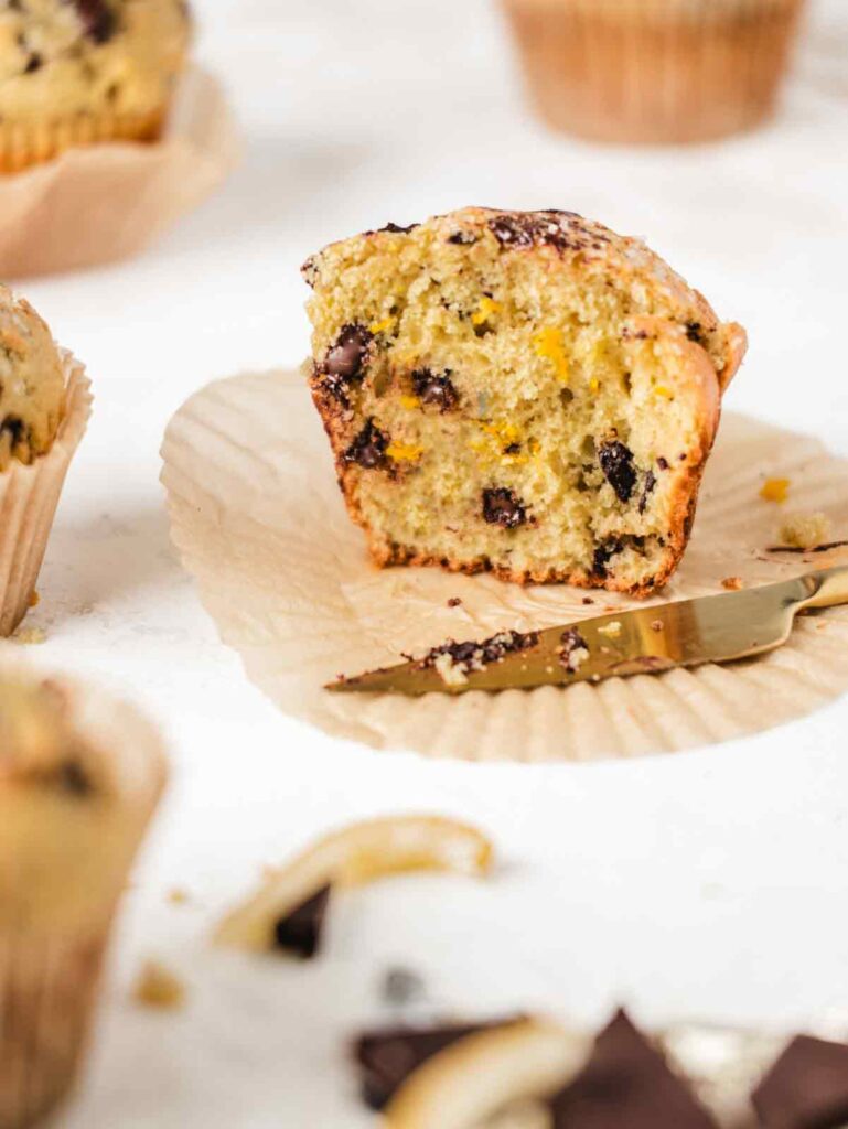 Muffin sliced in half with chocolate chips and chocolate on knife.
