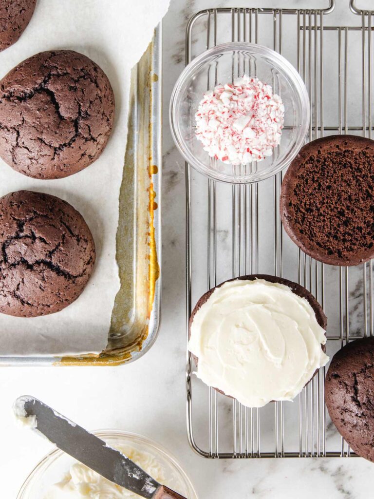 Whoopie pies on tray getting filled with buttercream.