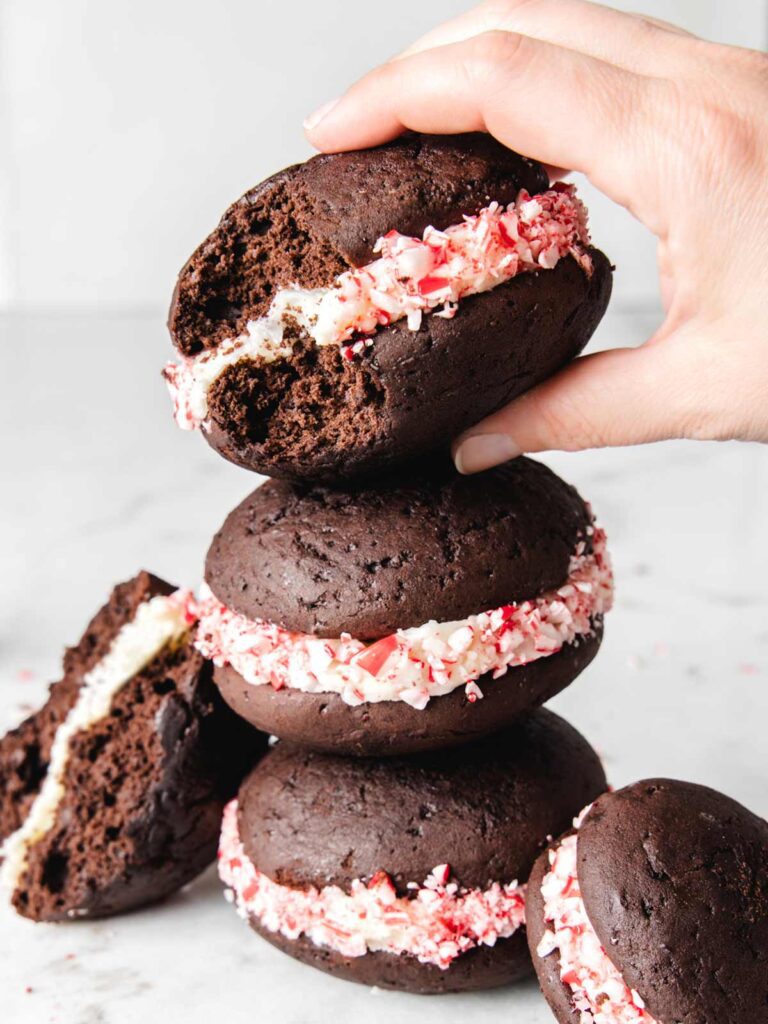 Stack of chocolate cakes with crushed peppermint coating and person picking up up the top cake.