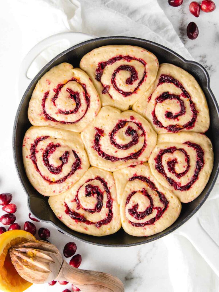 Proofed rolls with cranberry jam in cast iron pan.